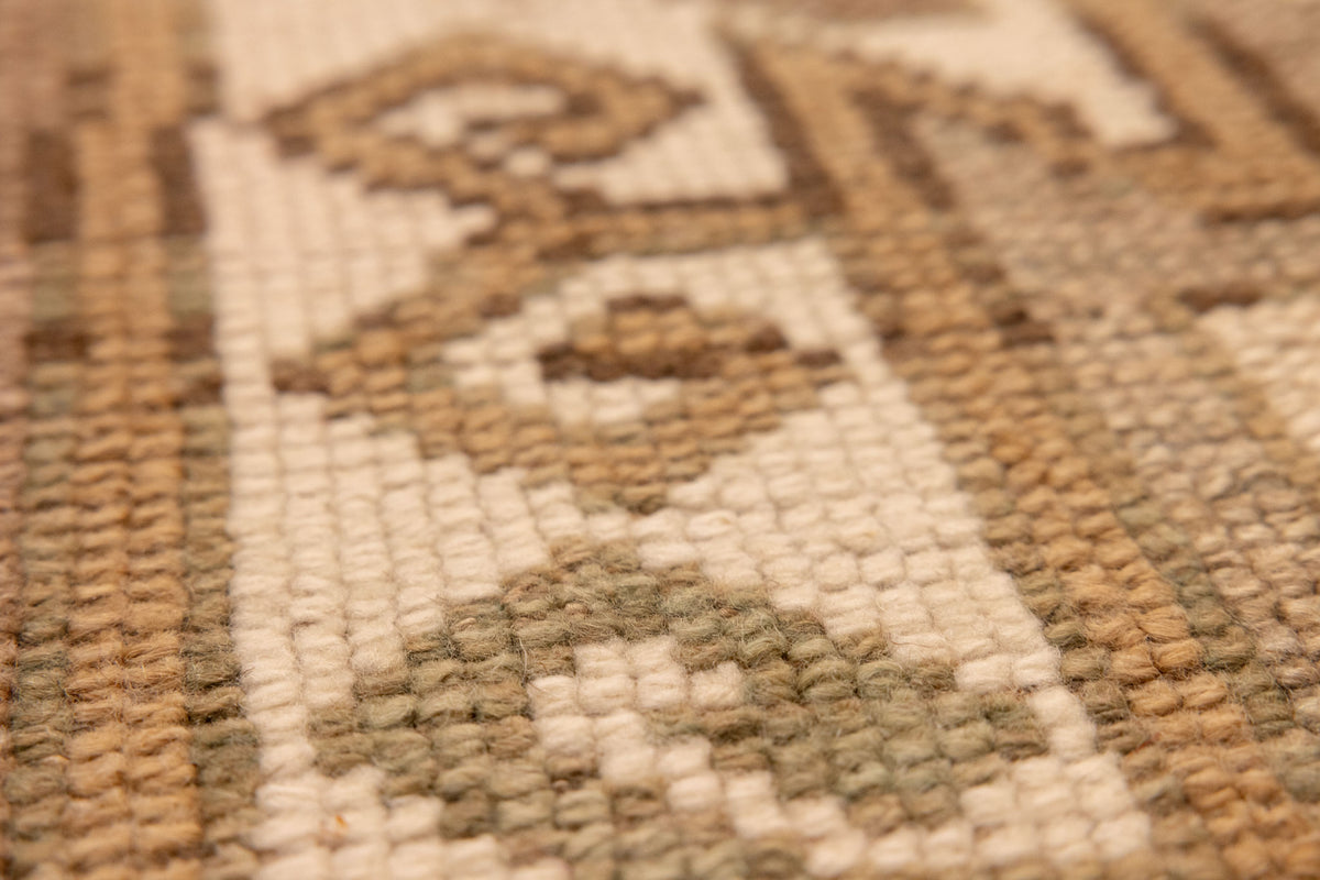 Close-up of a hand-woven vintage Turkish wool runner rug featuring detailed geometric patterns in earthy tones.