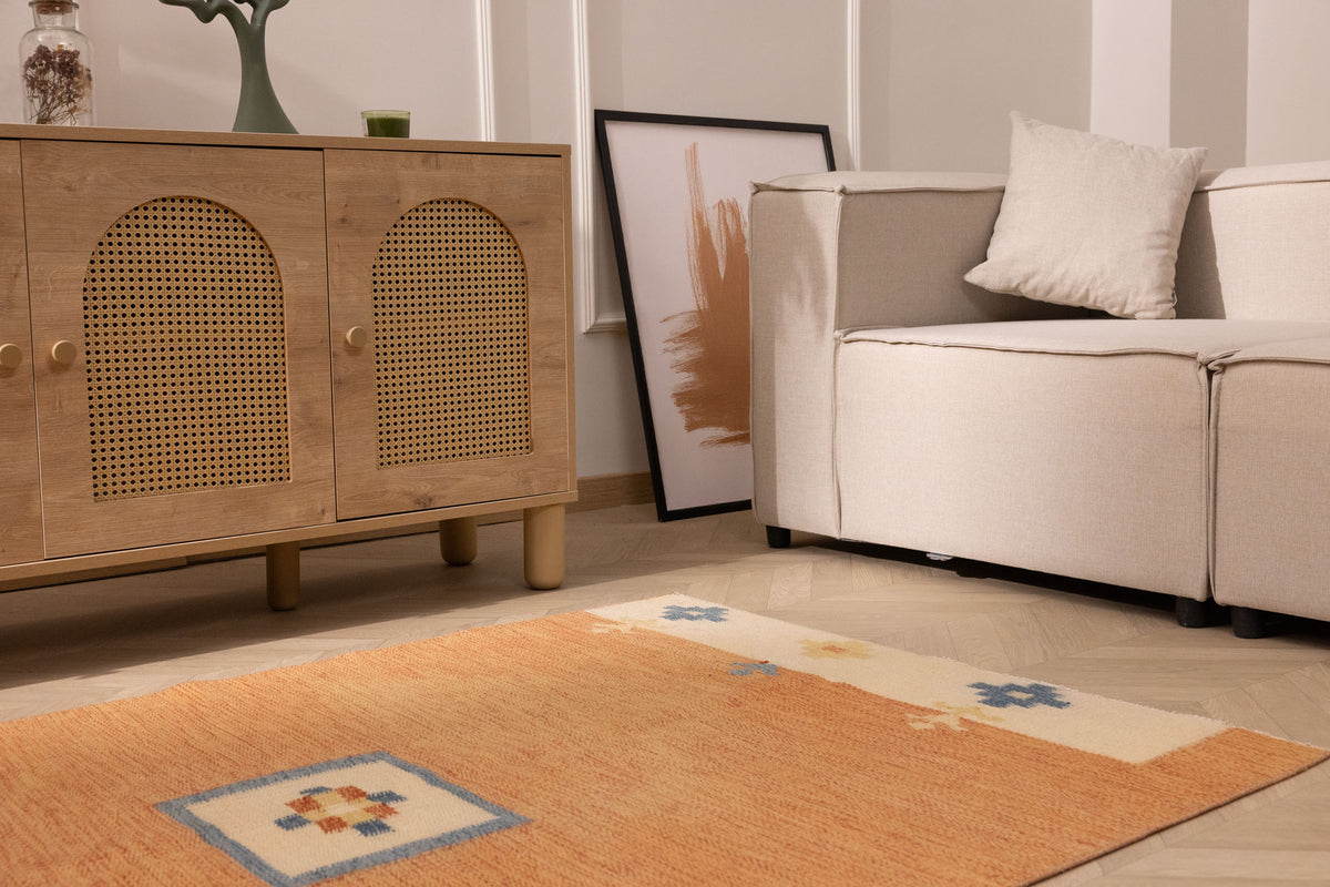 Hand-woven 3x5 ft vintage Turkish area rug in orange and beige with geometric patterns in a minimalist living room.