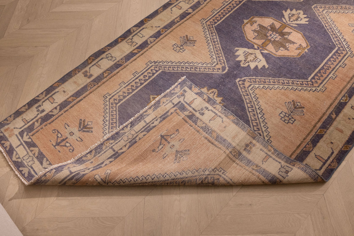 Vintage 4x12 ft Turkish runner rug in orange and navy wool with geometric tribal patterns on a hardwood floor.