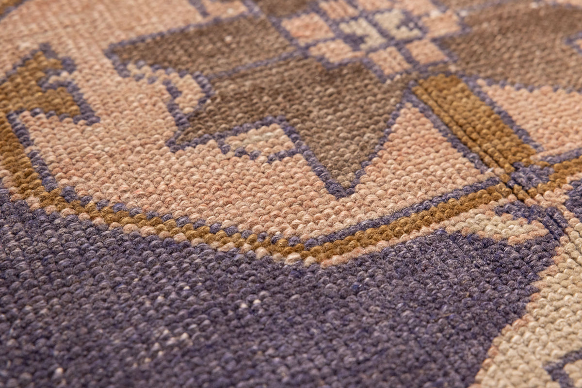 Close-up of a vintage Turkish wool and cotton runner rug featuring orange and navy geometric tribal patterns.