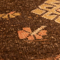 Close-up of a vintage Turkish wool runner rug featuring orange and brown geometric patterns and a textured weave.