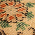 Close-up of a hand-woven vintage Isparta rug featuring white, red, and green floral patterns on a wool and cotton blend.