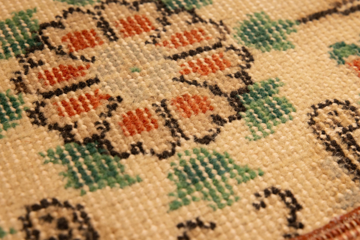 Close-up of a hand-woven vintage Isparta rug featuring white, red, and green floral patterns on a wool and cotton blend.
