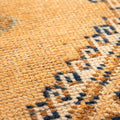 Close-up of a vintage Turkish wool runner rug featuring orange and brown geometric patterns and a textured, handwoven weave.