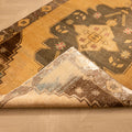Handwoven vintage Turkish runner rug in beige and gray with geometric patterns, featuring a folded corner showing wool texture.