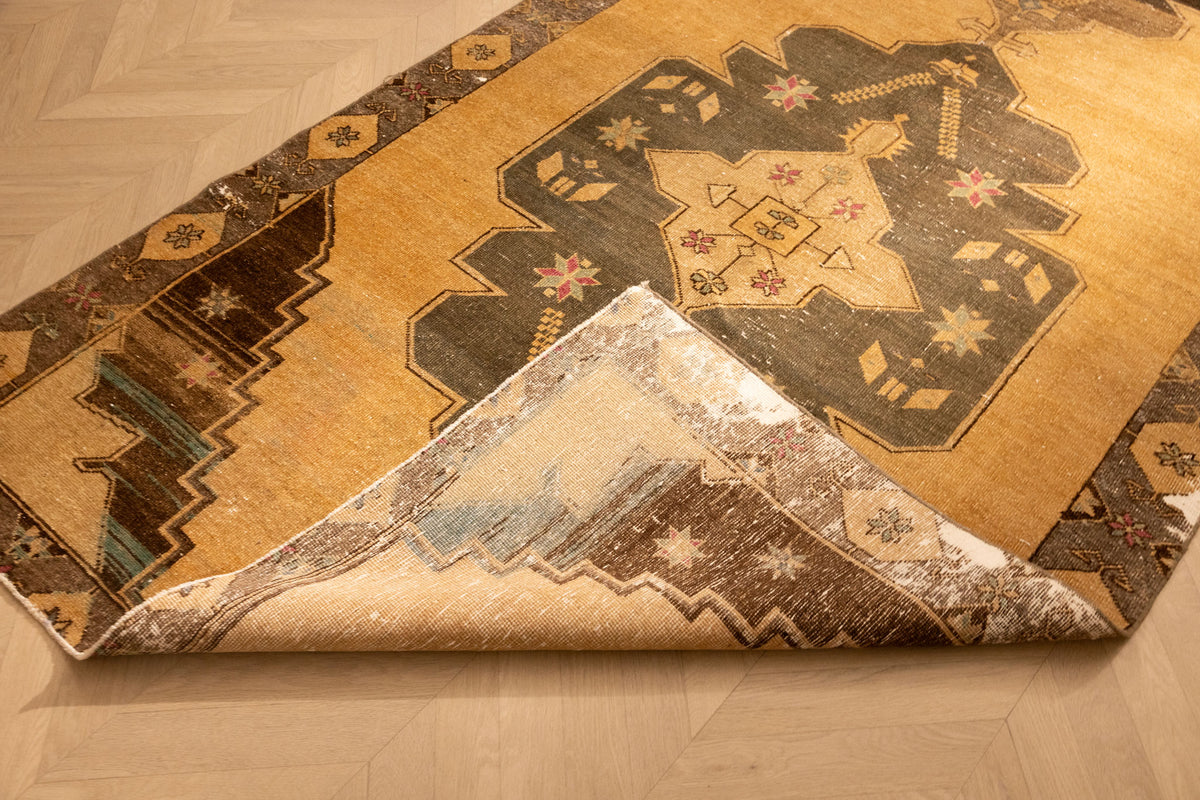 Handwoven vintage Turkish runner rug in beige and gray with geometric patterns, featuring a folded corner showing wool texture.