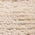 Close-up of a thick, cream-colored handwoven wool shaggy rug with a soft, dense, and textured pile surface.