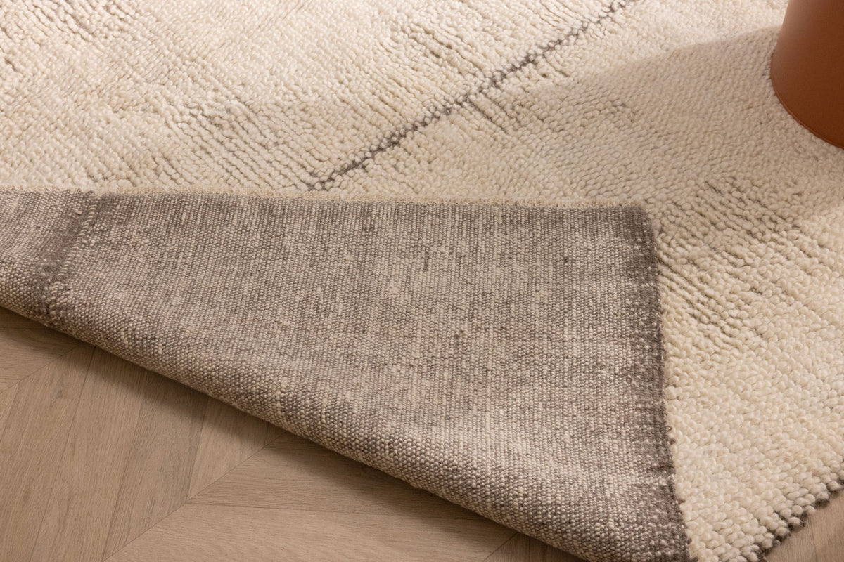 Handwoven brown and cream shaggy wool rug with a thick, textured pile and durable cotton backing on a wooden floor.