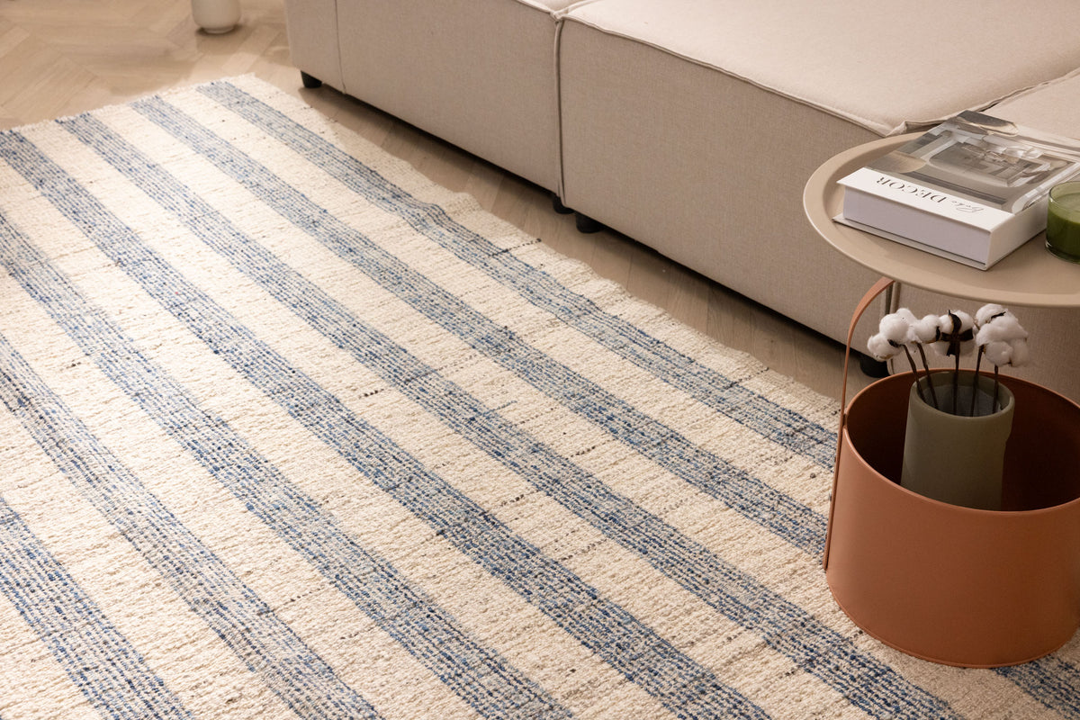 Handwoven white and blue striped wool-cotton flatweave rug in a modern living room setting.