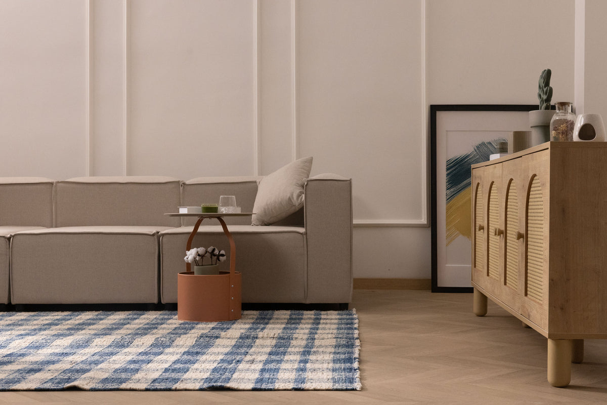 Blue and white checkered wool-blend flatweave rug in a modern living room with a beige sofa and wooden sideboard.