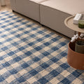 Blue and white checkered handwoven wool blend flatweave rug in a modern living room setting.