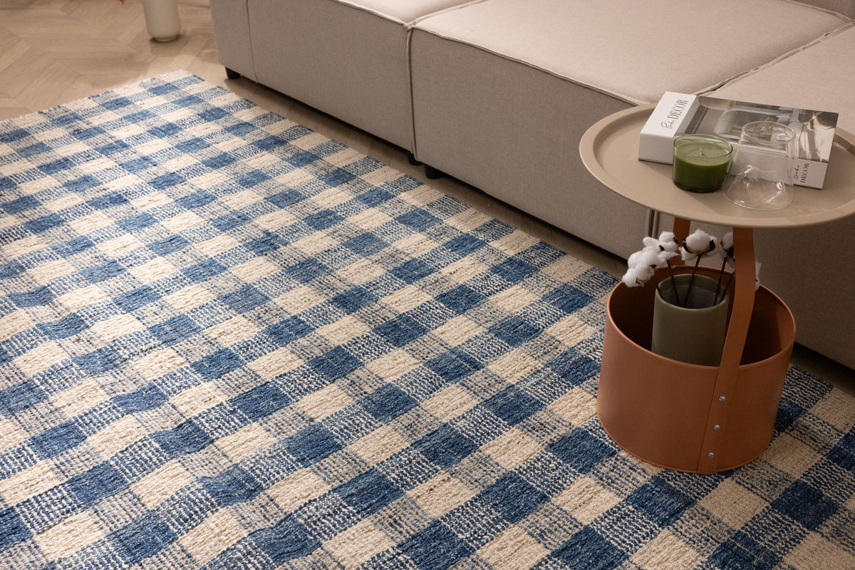 Blue and white checkered handwoven wool blend flatweave rug in a modern living room setting.