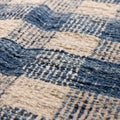 Close-up of a handwoven blue and white checkered wool-blend flatweave rug with a textured, durable finish.