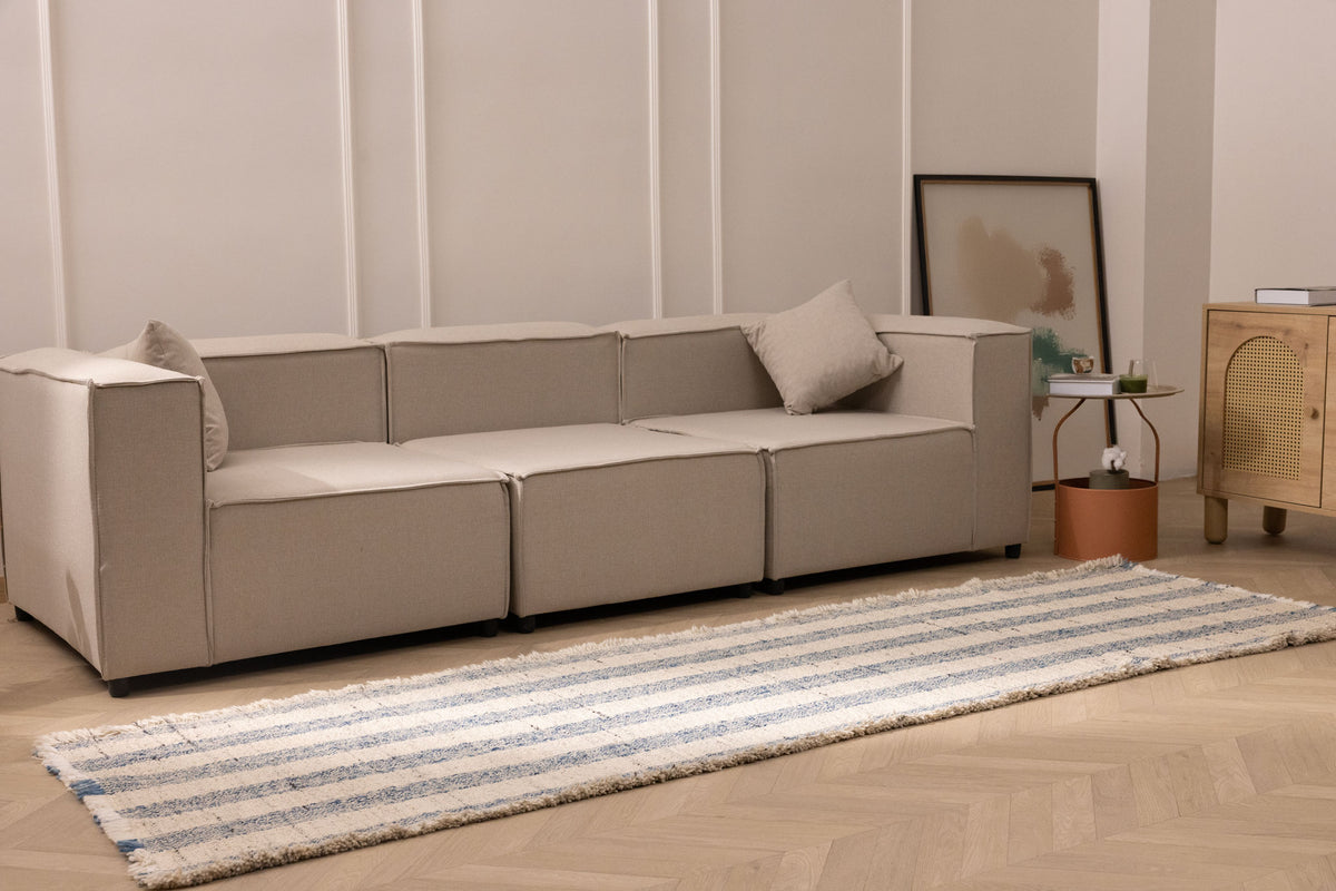 White and blue striped flatweave rug with fringed edges, crafted from wool and cotton in a modern living room setting.