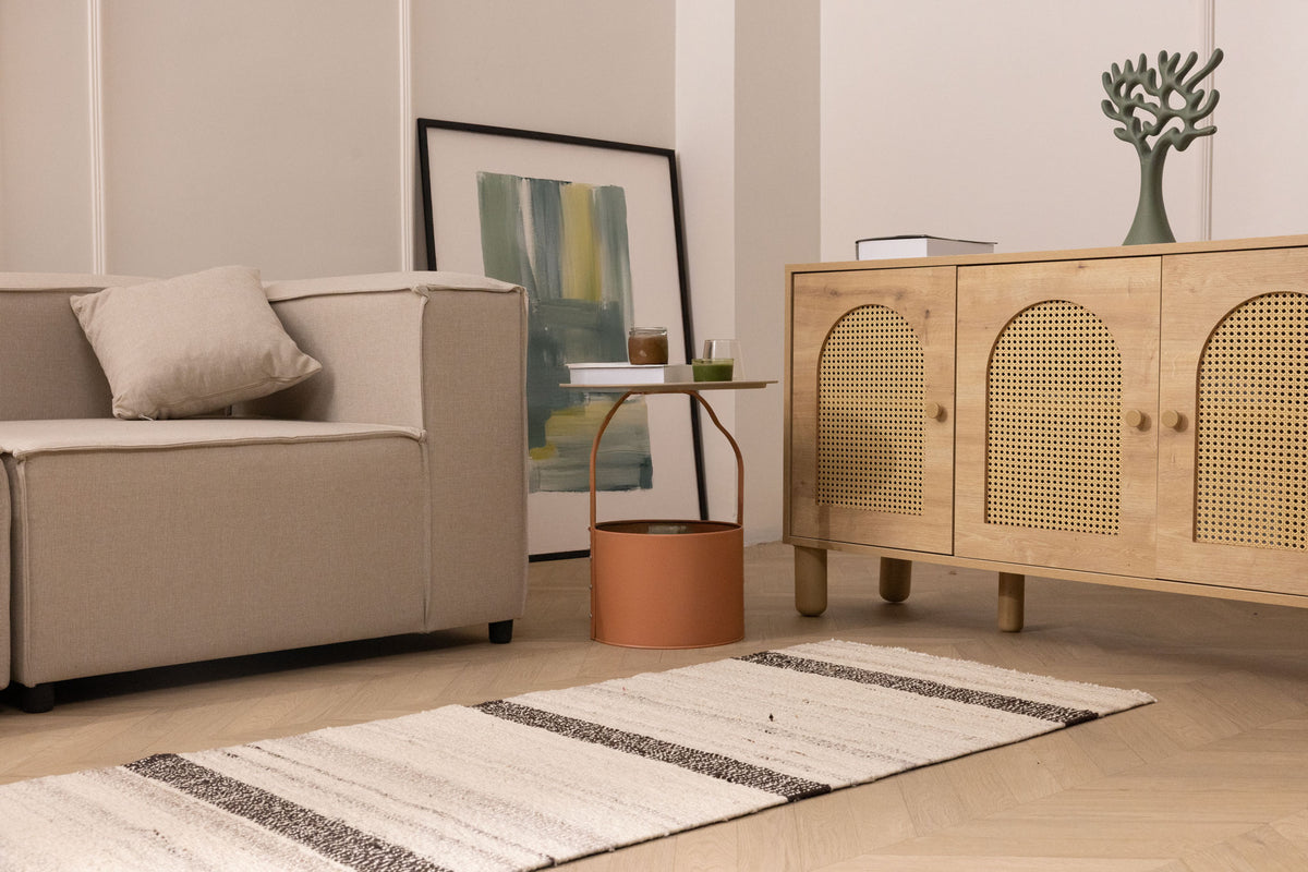 Handwoven white and black wool-blend flatweave rug with striped pattern on a light wood floor in a modern living room.