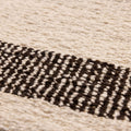 Close-up of a handwoven black and white wool-blend flatweave rug featuring a textured striped pattern.