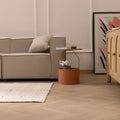 Minimalist white handwoven wool and cotton flatweave rug in a modern living room with herringbone wood flooring.