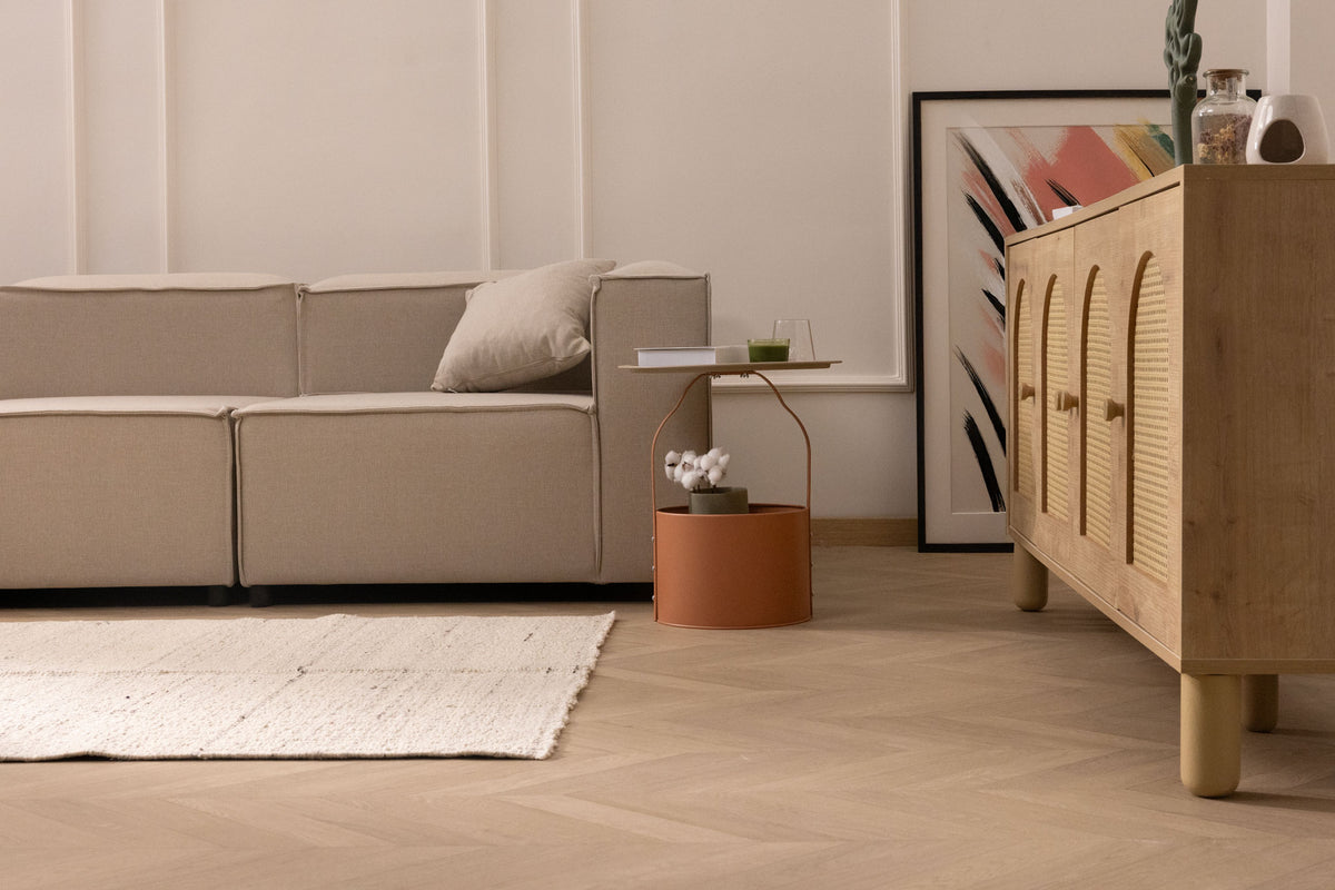Minimalist white handwoven wool and cotton flatweave rug in a modern living room with herringbone wood flooring.
