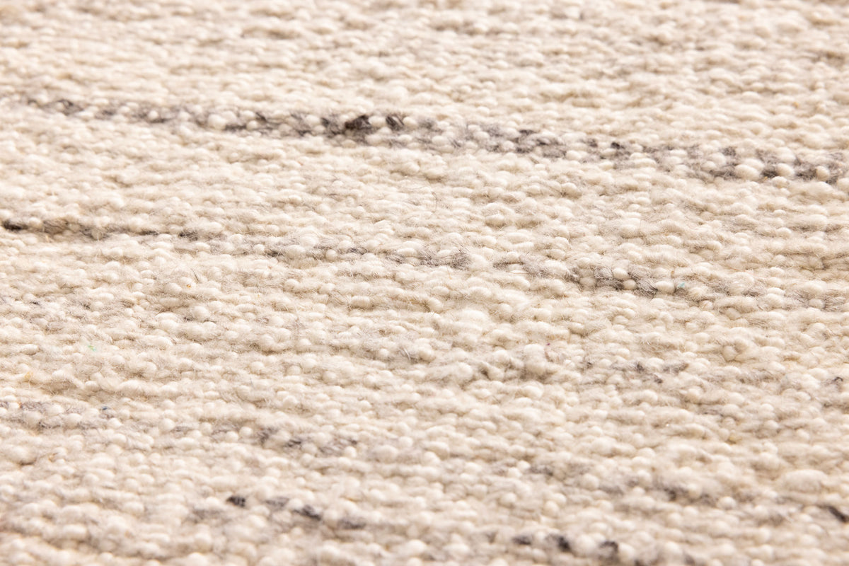 Close-up of a white handwoven wool and cotton flatweave rug with subtle grey horizontal striped texture.