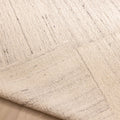 Handwoven white wool and cotton flatweave rug with subtle vertical textured stripes and a folded corner.