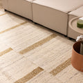 Handwoven white and brown wool-blend flatweave rug with a modern geometric striped pattern in a living room setting.