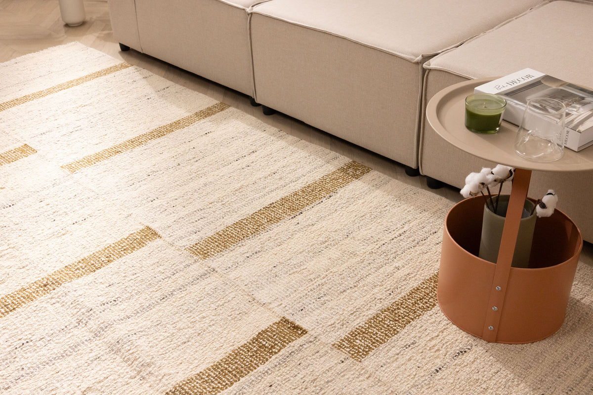 Handwoven white and brown wool-blend flatweave rug with a modern geometric striped pattern in a living room setting.