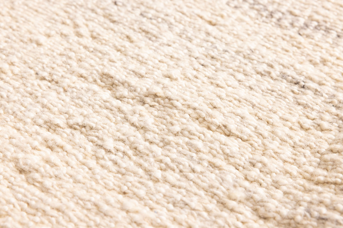 Close-up of a white and brown handwoven wool-blend flatweave rug with a textured, durable, and eco-friendly design.