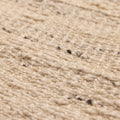 Close-up of a beige and brown handwoven wool-blend flatweave rug with a textured, durable, and eco-friendly design.