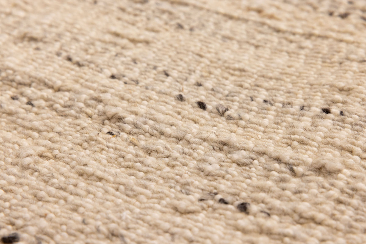 Close-up of a beige and brown handwoven wool-blend flatweave rug with a textured, durable, and eco-friendly design.