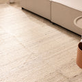 Handwoven white wool and cotton flatweave rug in a modern living room setting with neutral furniture.