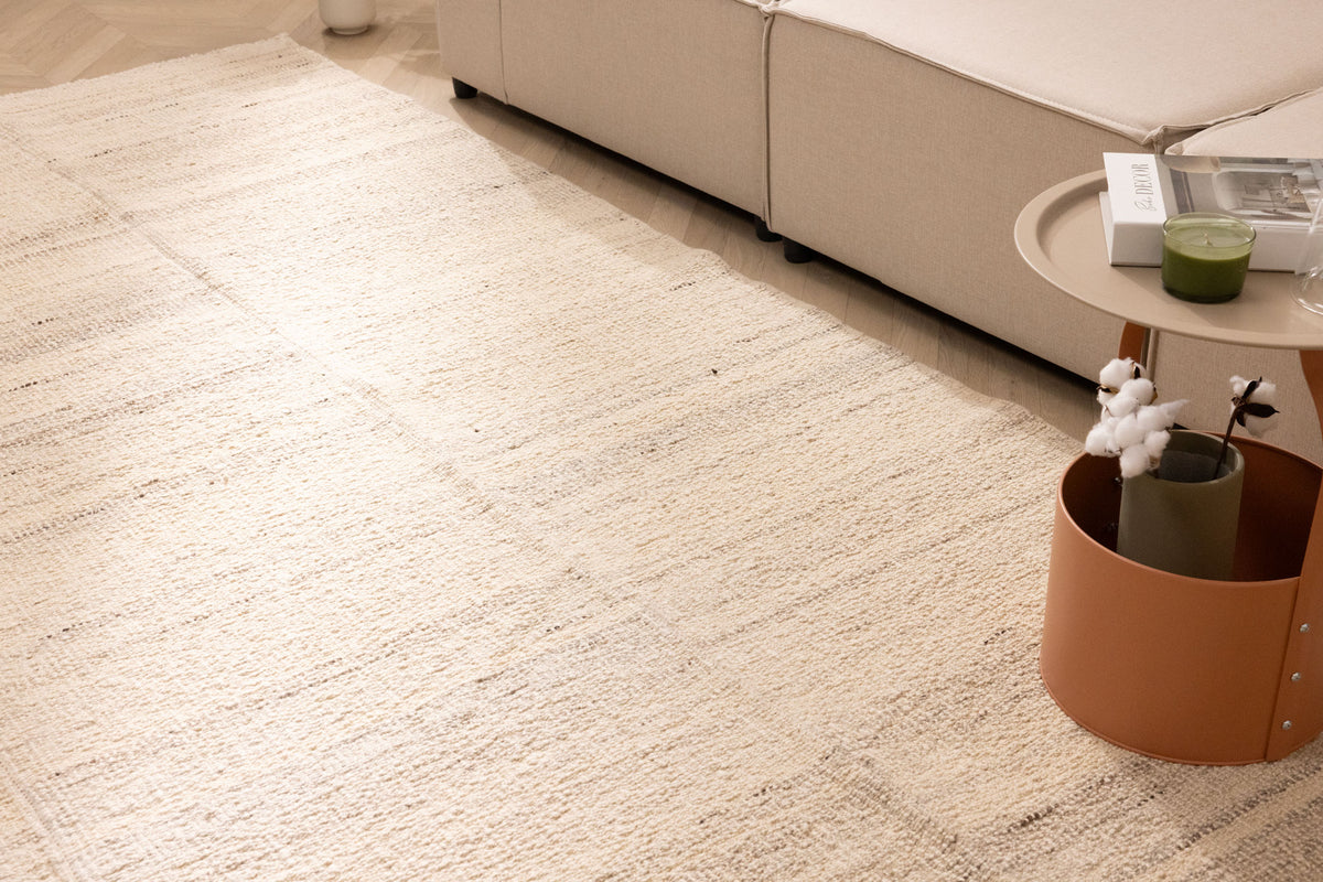 Handwoven white wool and cotton flatweave rug in a modern living room setting with neutral furniture.