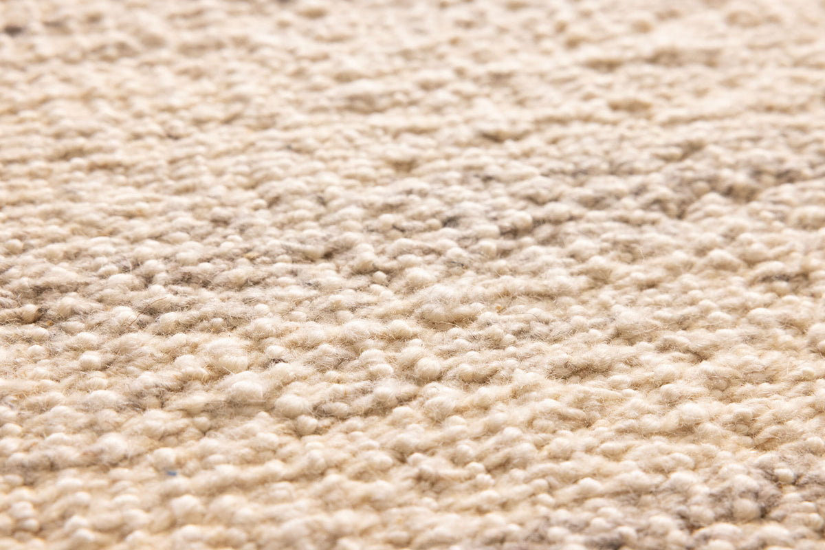Close-up of a white handwoven wool and cotton flatweave rug with a textured, durable surface.