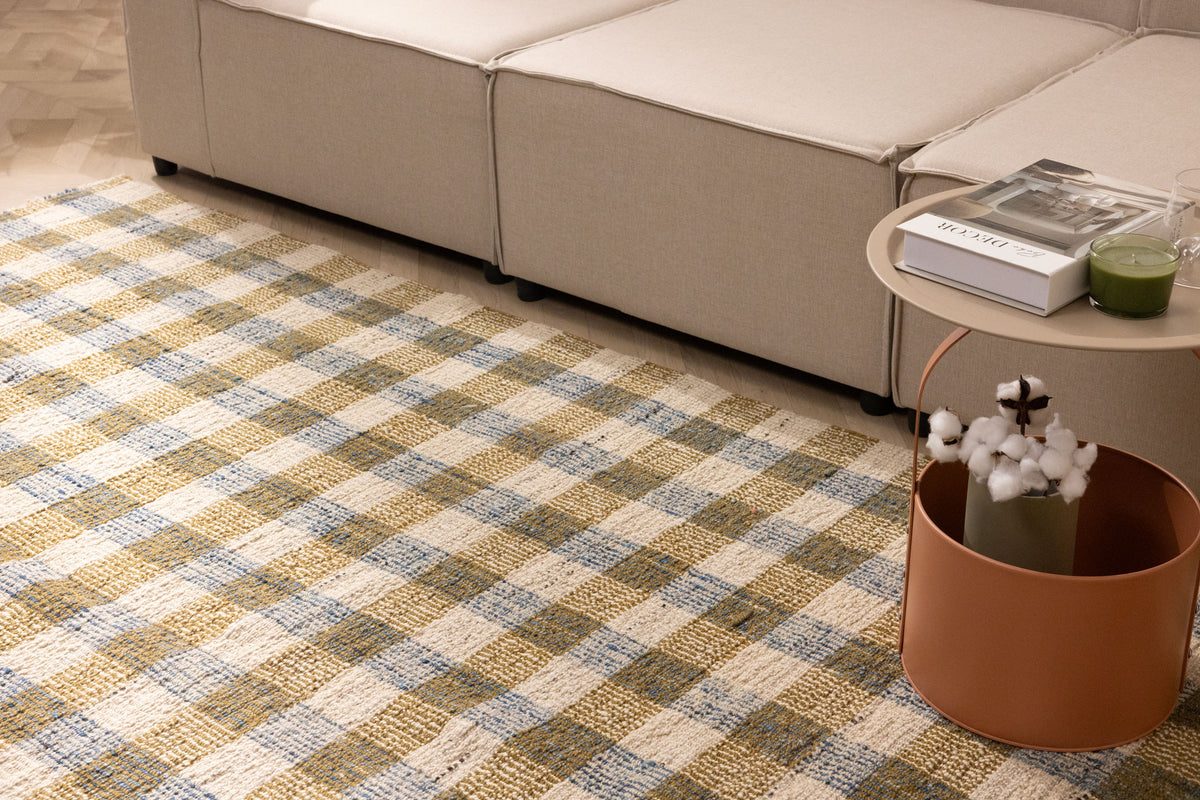 Handwoven white, brown, and blue checkered wool-blend flatweave rug in a modern living room setting.