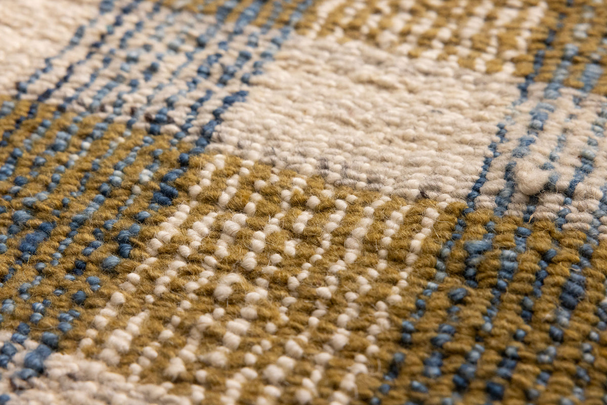 Close-up of a handwoven white, brown, and blue checkered flatweave rug made from a durable wool and cotton blend.