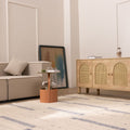Handwoven white and blue wool-blend flatweave rug in a modern living room with a beige sofa and rattan sideboard.