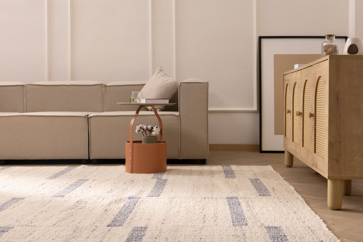 Handwoven white and blue wool-blend flatweave rug with a minimalist geometric pattern in a modern living room.