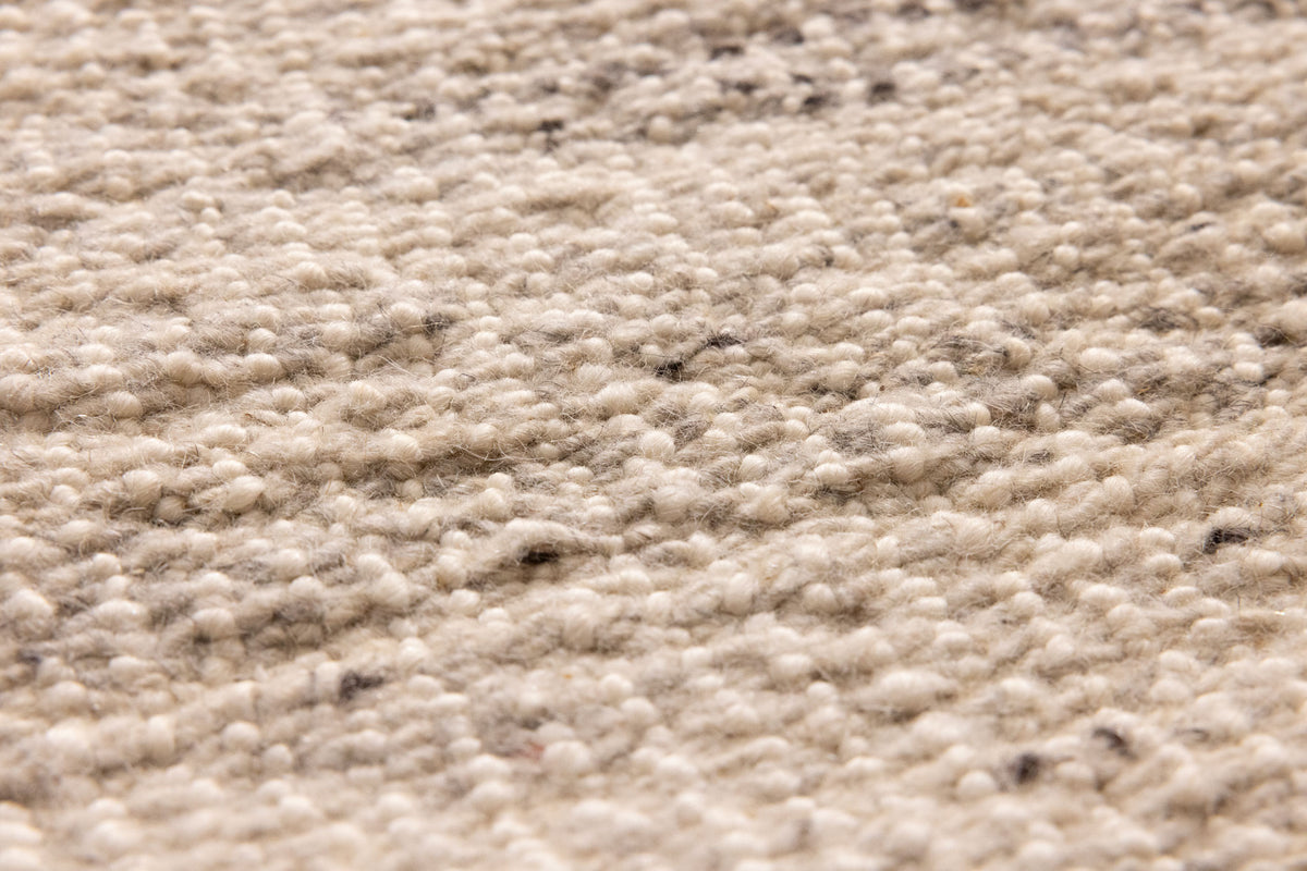 Close-up of a handwoven white and blue wool-blend flatweave rug with a textured, durable, and eco-friendly design.