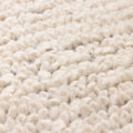 Close-up of a thick, cream-colored shaggy wool rug with a soft, handwoven high-pile texture.