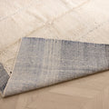 Handwoven sky blue and cream shaggy wool rug with a thick pile texture and durable cotton backing on a wooden floor.
