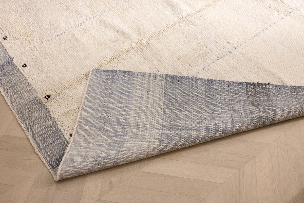 Handwoven sky blue and cream shaggy wool rug with a thick pile texture and durable cotton backing on a wooden floor.