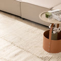 Cream-colored handwoven shaggy wool rug with a thick, textured pile placed in a cozy living room setting.
