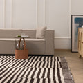 Handwoven shaggy wool rug with a black and white striped pattern, featuring a thick, high-pile texture in a modern living room.