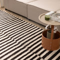 Handwoven black and cream striped shaggy wool rug with a thick, textured pile in a cozy modern living room setting.