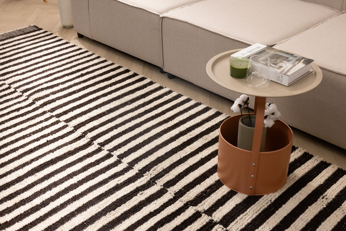 Handwoven black and cream striped shaggy wool rug with a thick, textured pile in a cozy modern living room setting.