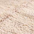 Close-up of a thick, cream-colored wool shaggy rug with a soft, high-pile textured weave.