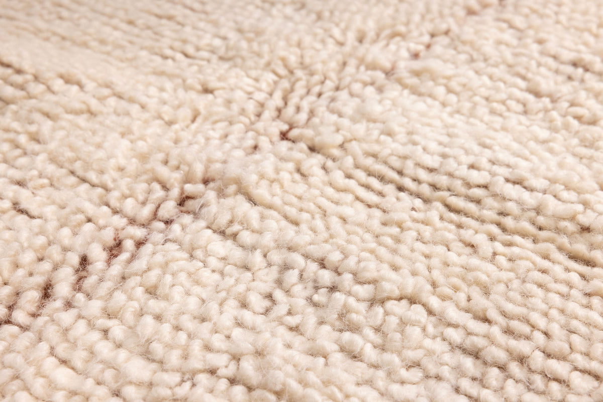 Close-up of a thick, cream-colored wool shaggy rug with a soft, high-pile textured weave.