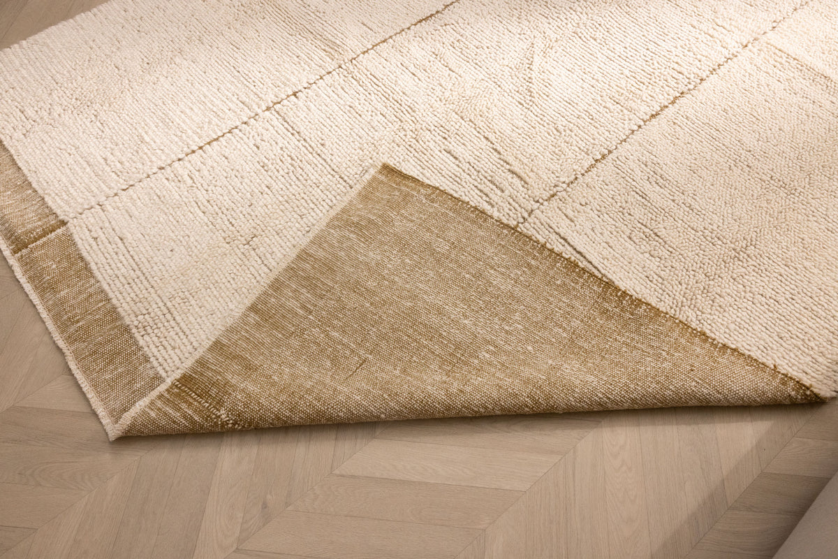 Dark mustard shaggy wool rug with a thick, textured pile and a folded corner revealing the smooth, durable backing.