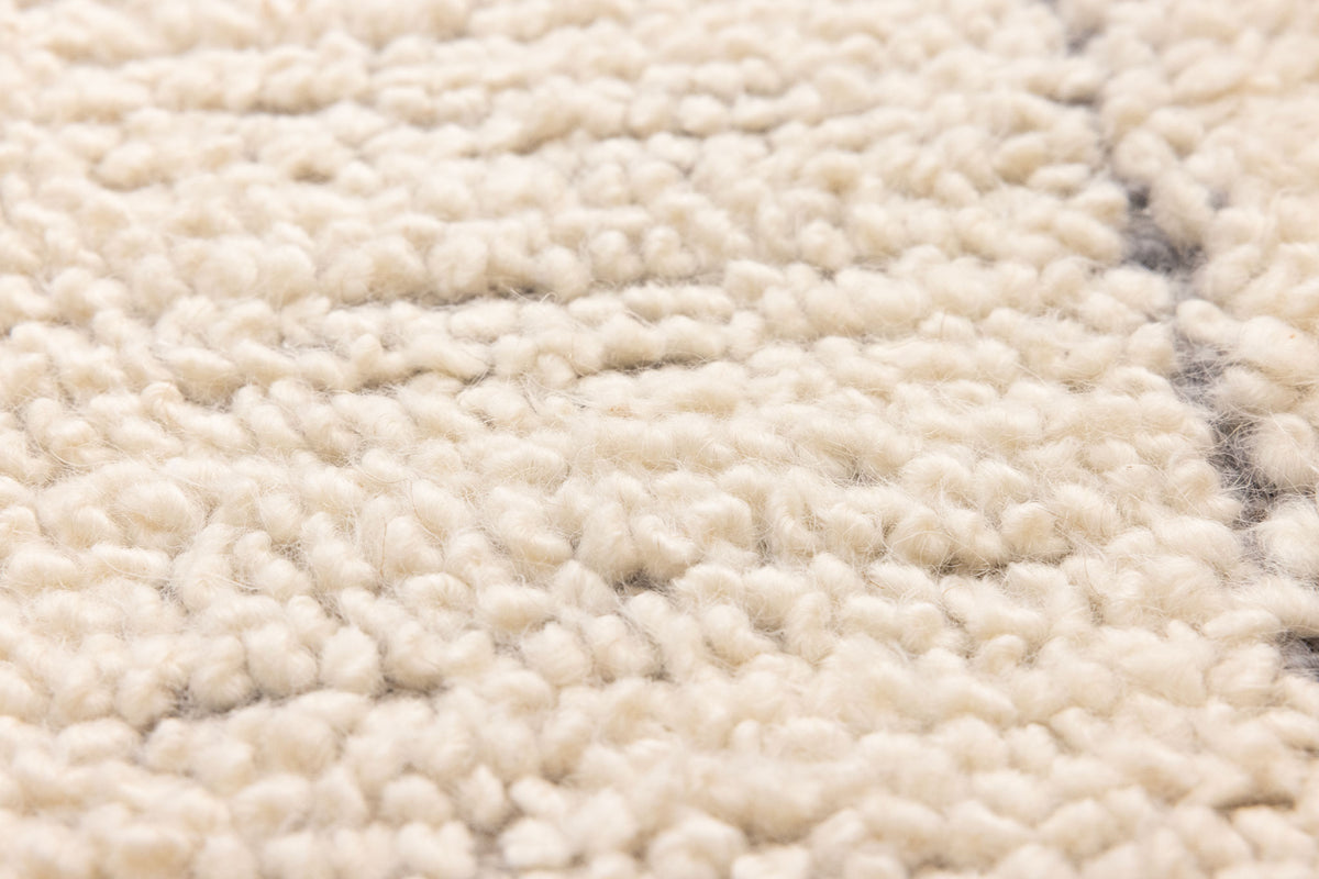 Close-up of a thick, silver-gray shaggy wool rug with a soft, handwoven high-pile texture and dense, cozy fibers.