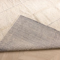 Silver gray shaggy wool rug with a high pile texture and a durable woven cotton backing, showing a folded corner detail.