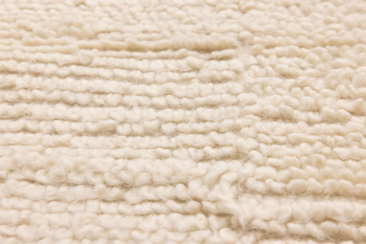 Close-up of a soft, white handwoven shaggy wool rug with a thick, textured high-pile design.